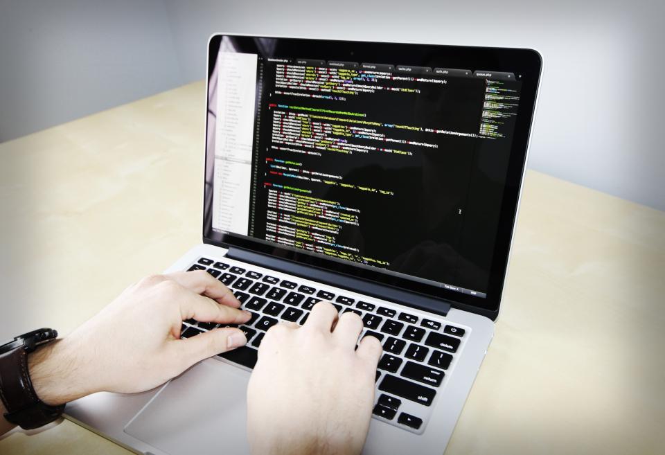 Ảnh kỹ sư đang làm việc với laptop hiển thị code hoặc trao đổi trước bảng trắng trong văn phòng, gợi bối cảnh xử lý dữ liệu ticket của khách hàng.