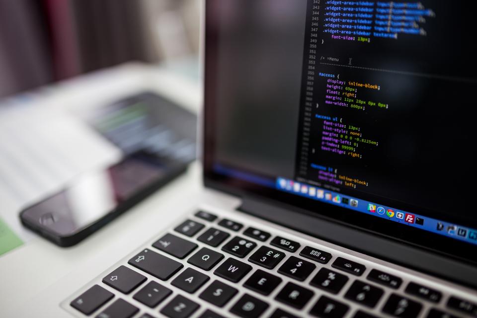 Kỹ sư ngồi trước laptop hiển thị mã nguồn và dữ liệu, không khí làm việc tập trung tại văn phòng.